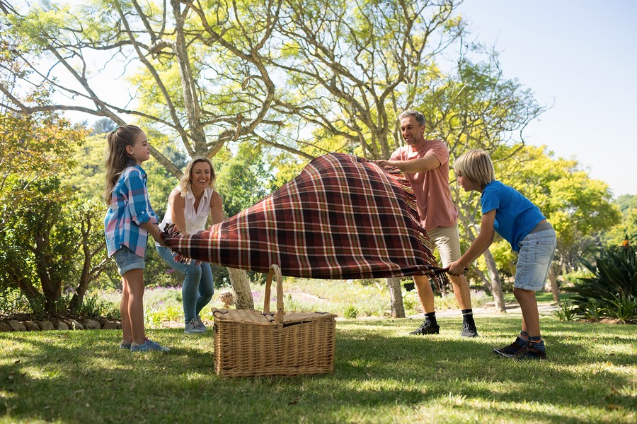 Family spreading the picnic blanket in park
