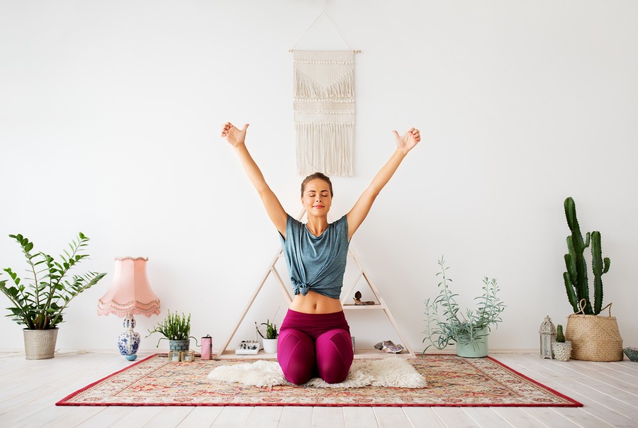 mindfulness, spirituality and healthy lifestyle concept - woman meditating at yoga studio