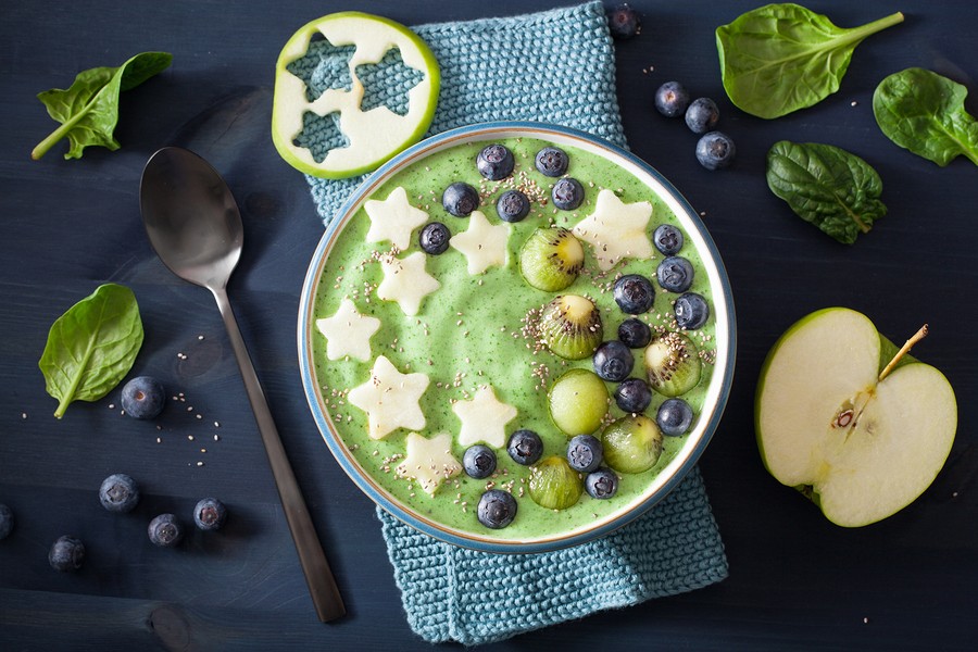 healthy green spinach smoothie bowl with blueberry, apple stars, kiwi, chia seed